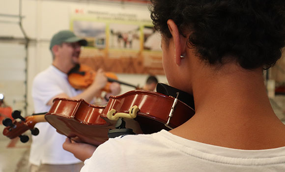 Um professor dá aulas de violino aos seus alunos
