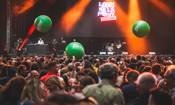 Live concert with large green Binter balloons floating over the crowd.