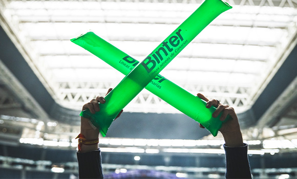 Two green inflatable sticks with the Binter logo raised in a stadium.