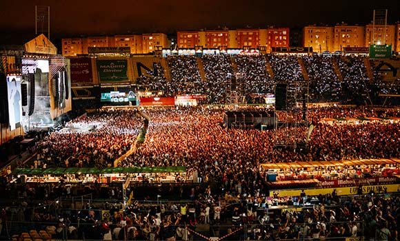 Panoramic view of a large concert in a lit-up stadium.