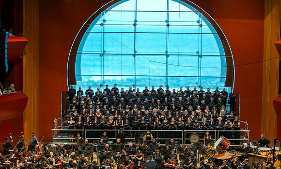 Orchestra and choir performing in a concert at an auditorium.