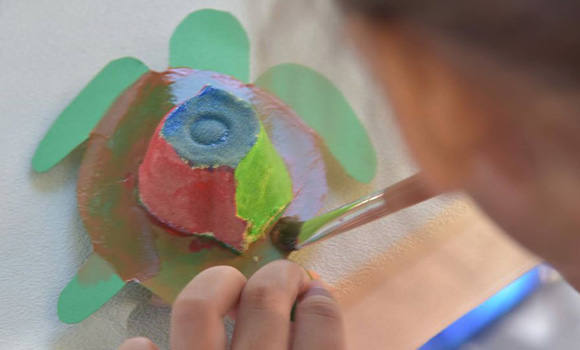 Un voluntario pintando manualidad en forma de tortuga