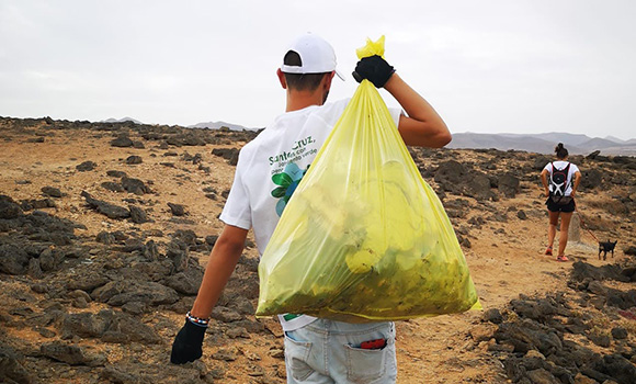 Un volontario che trasporta un sacco durante la pulizia della spiaggia.