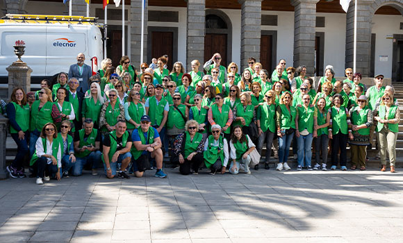 Large group of people wearing green vests posing in front of a building.