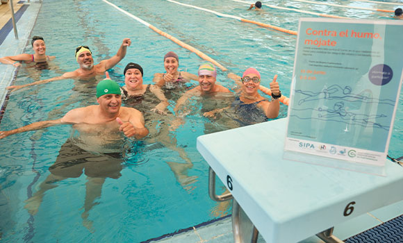 Group of smiling swimmers in a pool during an awareness campaign.