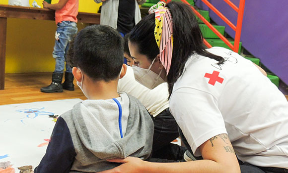 Red Cross volunteer playing with several children