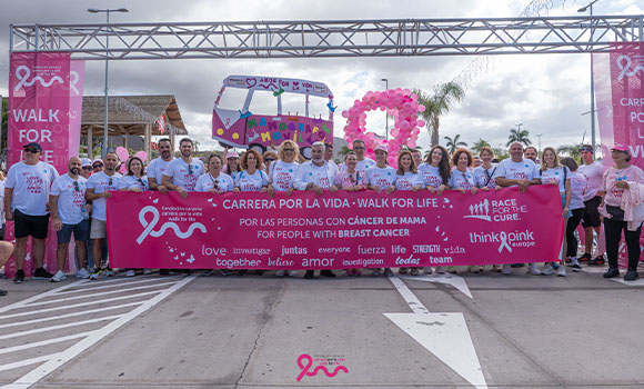 Group of people holding a banner at a breast cancer walk.