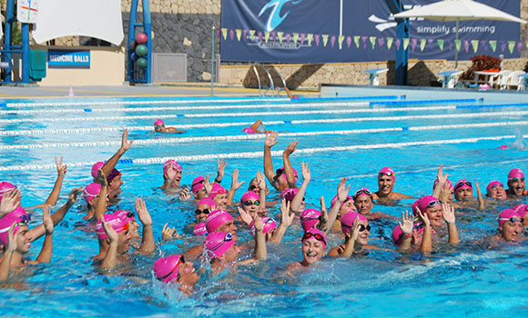 Group of swimmers in a pool, all wearing pink caps.