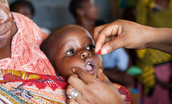 Primo piano di un bambino che riceve farmaci mentre apre la bocca.