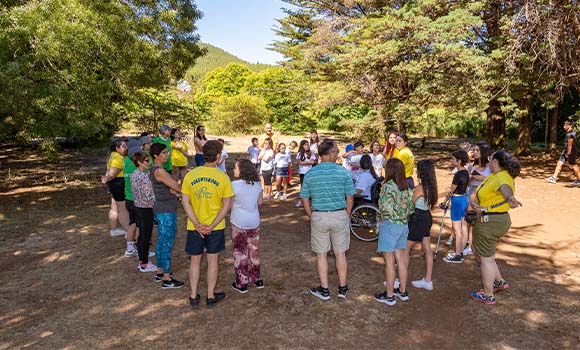 Grupo de personas en un círculo al aire libre, participando en una actividad grupal.