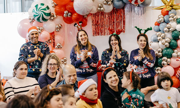 Grupo de personas aplaudiendo en un evento festivo decorado con globos.