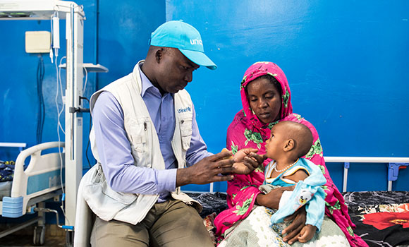 Um voluntário da Unicef cuida de uma criança.